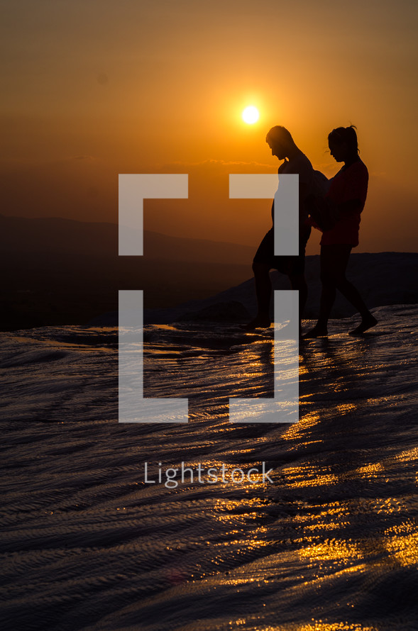 a couple walking atop Pamukkale in Turkey at sunset 