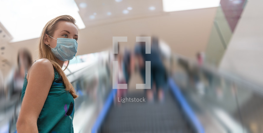 Urban city lifestyle. Young woman with face mask in modern shopping mall.