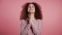 Cute european young girl praying over pink background