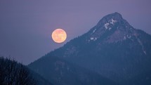 Full moon rising over alpine mountains Time lapse
