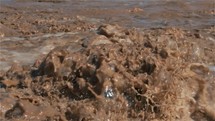 Slow motion of muddy water of flooded river splashing after heavy storm rainfall
