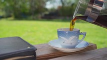 tea cup and Bible on a bench 