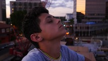 A teenage boy in prayer in an urban setting
