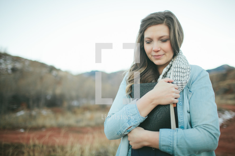 woman holding a Bible close to her heart 