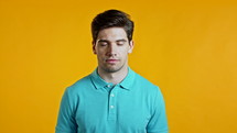 Portrait of handsome man in blue t-shirt looking to camera. Guy in studio on bright yellow background. High quality 4k footage