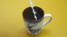 Pouring steaming fresh natural milk into a mug for breakfast 