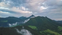 Aerial view of Green forest landscape with fast moving clods over mountains Time lapse
