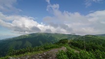 Beautiful white clouds flying over green mountains and blue sky landscape time lapse
