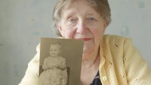 elderly woman looking at an old photo album 