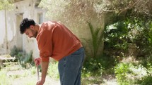 Boy Sweeps With Broom Outside Near Fountain In Countryside