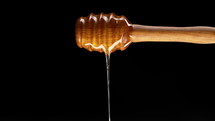 Natural wooden honey spoon: dipper stick with dripping flower healthy nectar on black background. Useful kitchen tools, High quality 4k footage