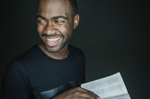 man smiling holding an open Bible 