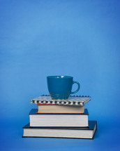 blue coffee cup on a stack of books 