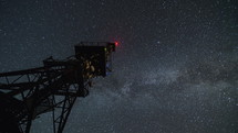 Communication tower in starry night time lapse. Moving stars sky with milky way galaxy
