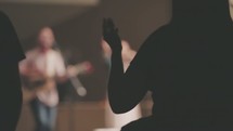 Silhouette of audience with arms raised at a worship concert.