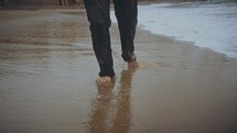 a man walking barefoot on a beach 
