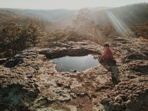child sitting by a puddle on a mountaintop 