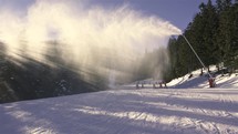 Magic light of sun in winter ski resort, making snow with a snow cannon, holiday recreation
