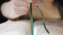 Slow motion of a woman putting the ribbon bookmark between Bible pages.