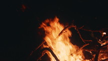 Tree branches burning in a campfire at night in slow motion