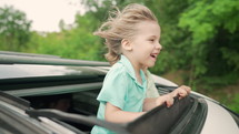 Adorable happy little kids stands in open car sunroof during road trip in countryside at summer. Concept of family leisure, active traveling. High quality 4k. 