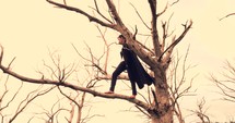a boy in a cape standing in a tree 