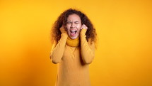 Young, scared, girl shouting isolated over yellow background. Stressed and depressed woman.