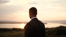 groom standing outdoors at sunset 