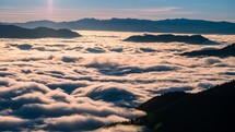Low clouds flow like a river in alpine mountains valley in beautiful autumn nature landscape time-lapse

