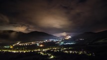Epic clouds moving over village lighting at starry night Time-lapse
