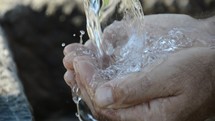 cupped hands catching flowing water 