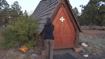 A woman entering a small chapel to pray
