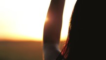 Freedom concept. Silhouette of a beautiful young woman at sunset in the field. Happy woman is dreaming. The best moments of life, serenity and happiness.
