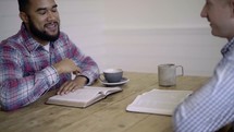 two men having a conversation over coffee and discussing scripture 