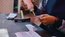 Woman putting glue on a leather wallet in a leather workshop