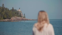 a woman looking out at a lighthouse 