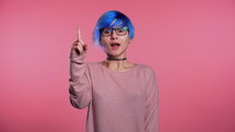 Portrait of young thinking pondering woman having idea moment pointing finger up on pink studio background. High quality 4k footage