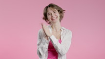 Happy stylish woman applauding on pink background. Smiling lady emotional claps hands, congratulating. Support, cheering, gratitude concept