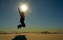 Silhouette of a person jumping off the ground on a sunny day.
