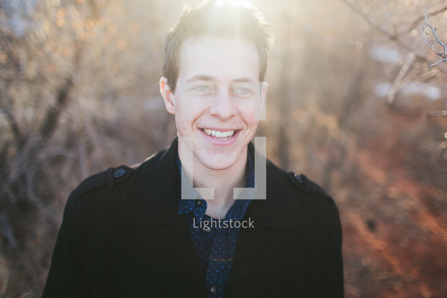 smiling man standing outdoors in sunlight 