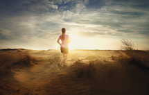 woman jogging on sand dunes at sunrise 