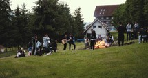 people sitting around a campfire playing music 
