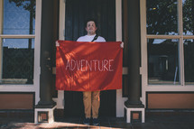 A man holding a red banner with the word adventure on it. 