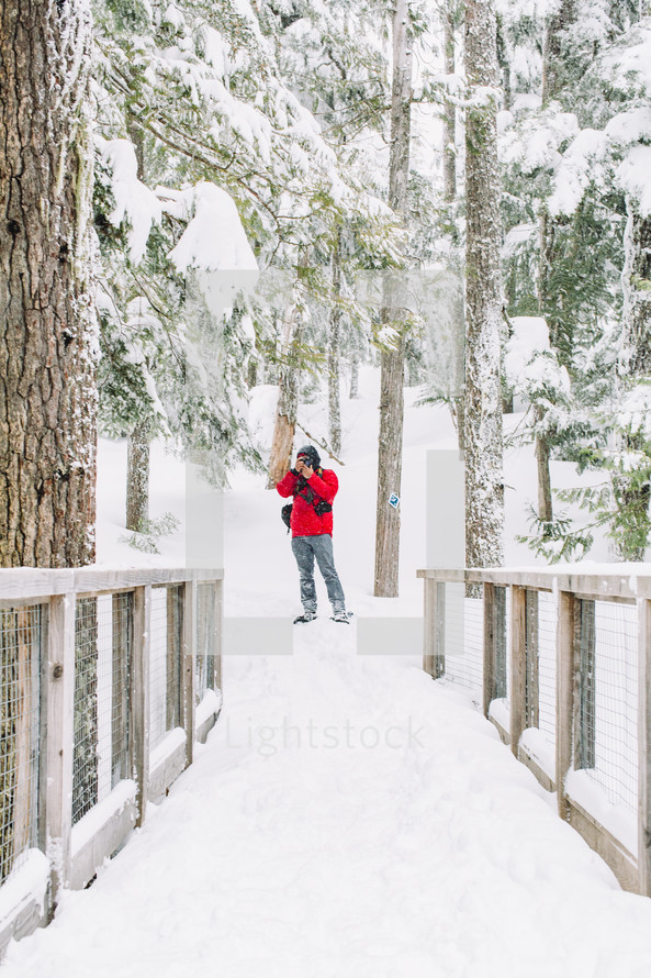 a man taking a picture in a winter forest 