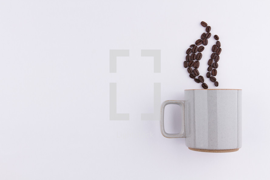 coffee beans in the shape of steam from a mug on a white background 