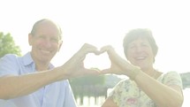 senior caucasian couple making heart shape with their hands