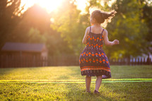 a girl in a sundress dancing in a back yard 