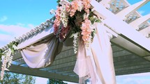 hydrangeas and white fabric hanging from a pergola 