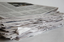 stacked newspapers on a white table.