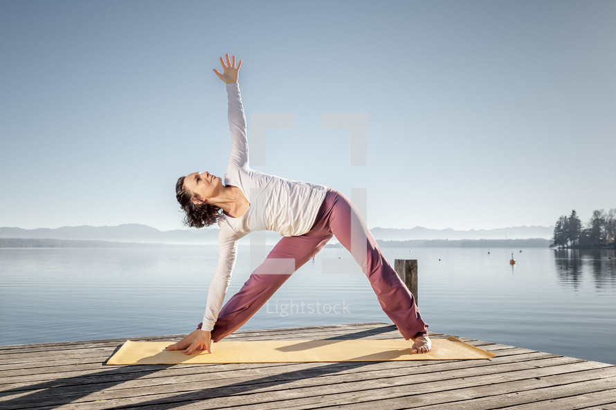 woman stretching and doing yoga on a dock 